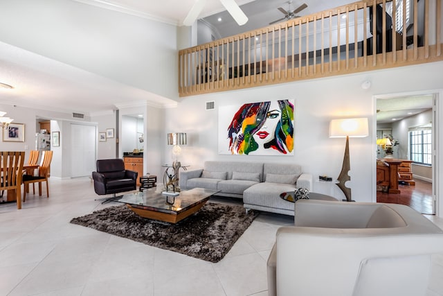 tiled living room with a towering ceiling, crown molding, and ceiling fan