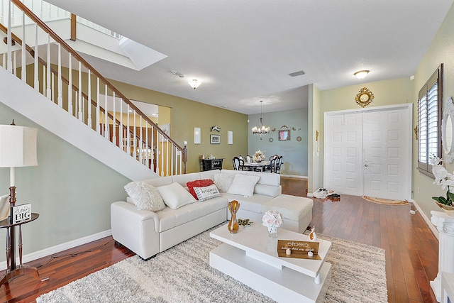 living room with a skylight, dark wood-type flooring, and a notable chandelier