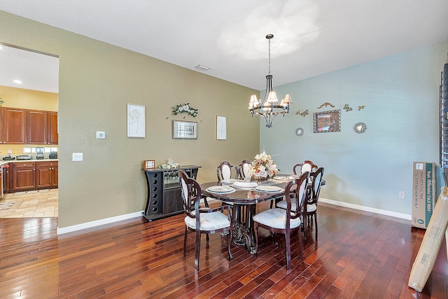 dining area with dark hardwood / wood-style floors and an inviting chandelier