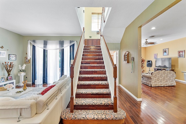 stairs featuring dark hardwood / wood-style flooring and ceiling fan