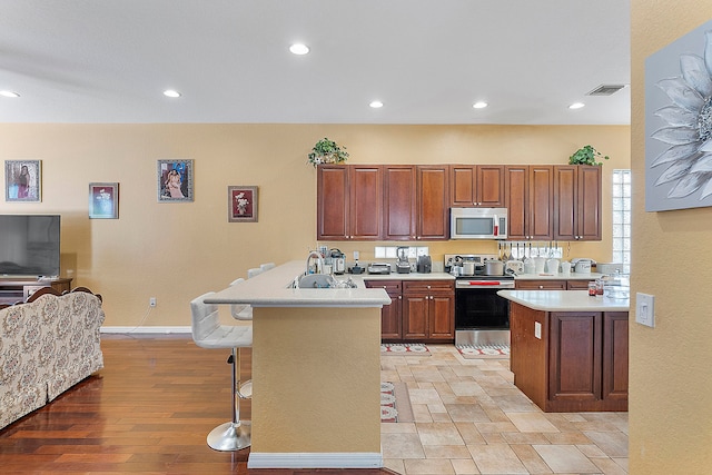 kitchen featuring appliances with stainless steel finishes, sink, light hardwood / wood-style floors, and a kitchen bar