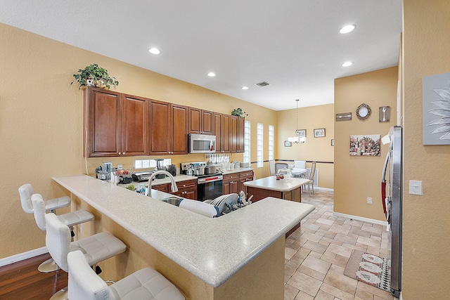 kitchen featuring appliances with stainless steel finishes, a kitchen island, hanging light fixtures, light tile flooring, and a kitchen breakfast bar