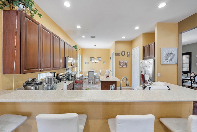 kitchen with stainless steel appliances, kitchen peninsula, decorative light fixtures, and a kitchen bar