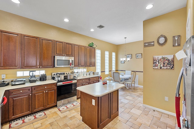 kitchen with a center island, appliances with stainless steel finishes, decorative light fixtures, and light tile floors