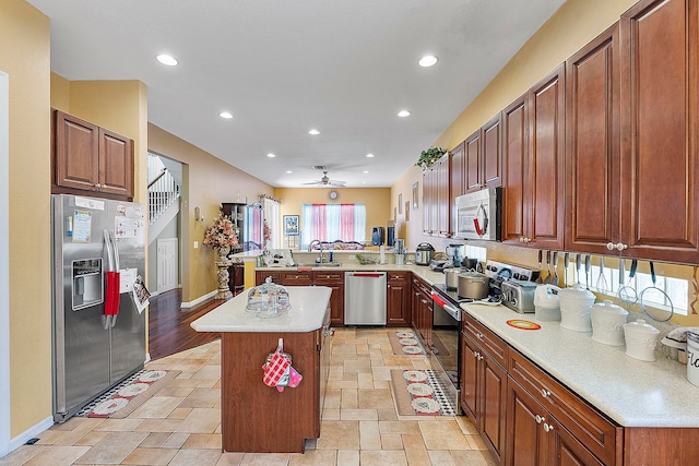 kitchen with kitchen peninsula, stainless steel appliances, sink, light tile floors, and ceiling fan