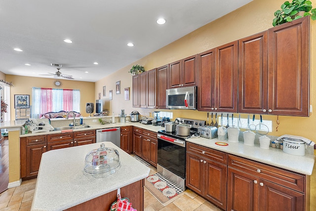 kitchen featuring ceiling fan, light tile floors, sink, stainless steel appliances, and kitchen peninsula