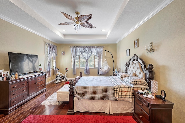 bedroom featuring crown molding, dark hardwood / wood-style floors, ceiling fan, and a tray ceiling