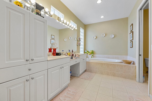 bathroom featuring a relaxing tiled bath, toilet, tile flooring, and vanity