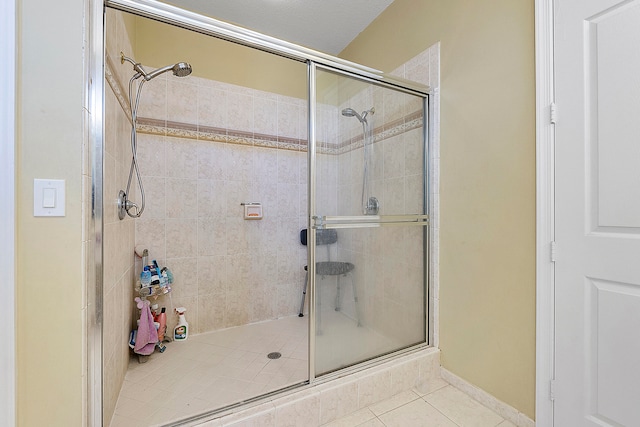 bathroom with a shower with shower door and tile floors