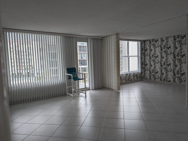 tiled spare room with a textured ceiling and plenty of natural light