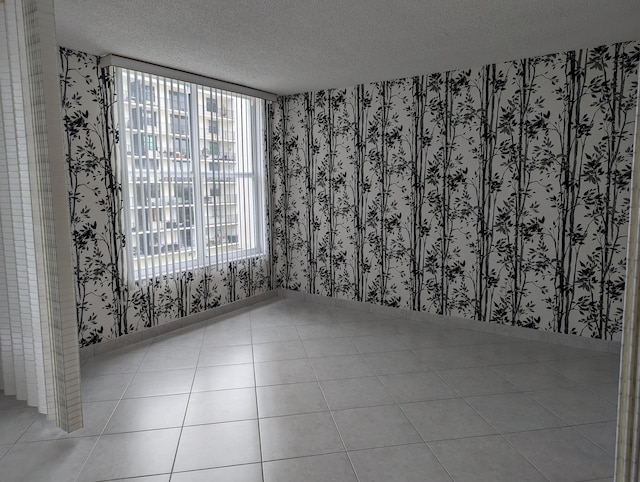 tiled empty room with a textured ceiling and a healthy amount of sunlight