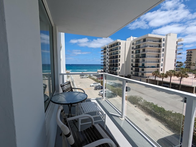 balcony with a water view and a view of the beach