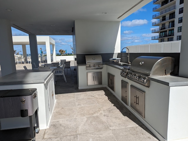 view of patio / terrace featuring a balcony, exterior kitchen, grilling area, and sink