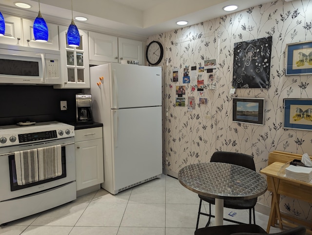 kitchen featuring white appliances, hanging light fixtures, white cabinetry, and light tile patterned flooring