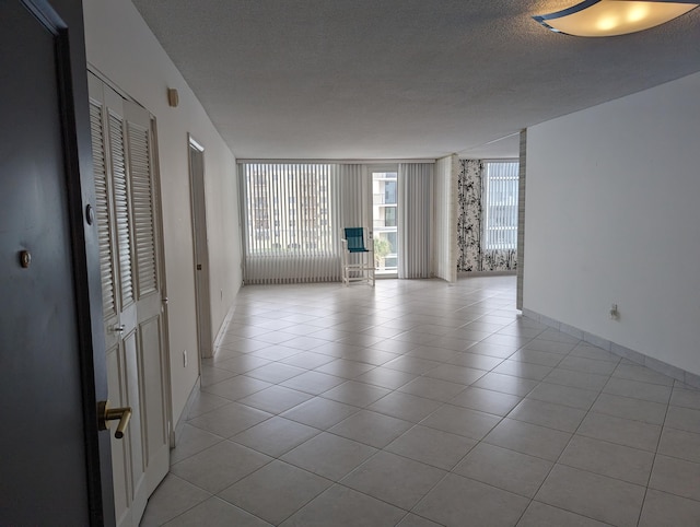 tiled empty room with a textured ceiling and a wall of windows