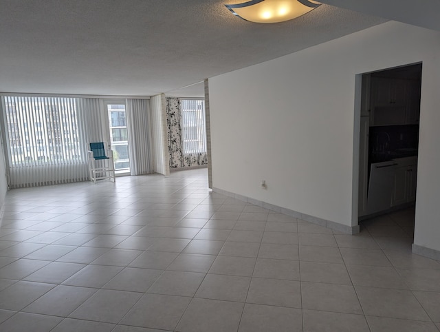 spare room with a textured ceiling, sink, and light tile patterned flooring