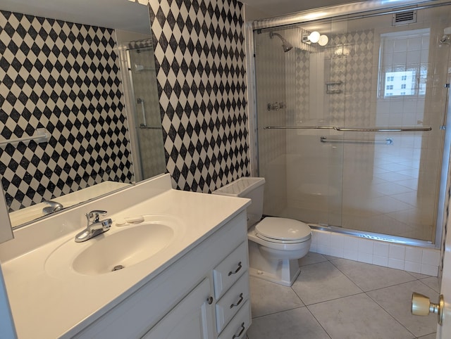 bathroom featuring vanity, toilet, a shower with shower door, and tile patterned flooring