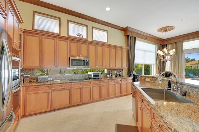 kitchen with a notable chandelier, ornamental molding, stainless steel appliances, sink, and hanging light fixtures