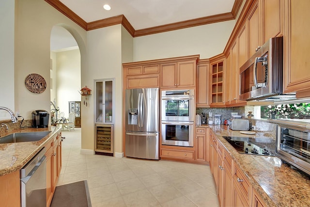 kitchen featuring light stone counters, stainless steel appliances, sink, beverage cooler, and tasteful backsplash