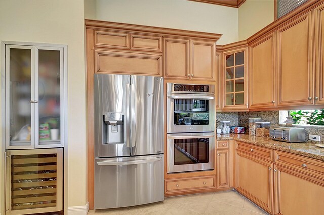 kitchen with appliances with stainless steel finishes, light stone counters, wine cooler, light tile patterned flooring, and decorative backsplash