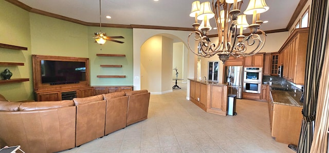 living room with light tile patterned floors, ornamental molding, ceiling fan with notable chandelier, and a towering ceiling