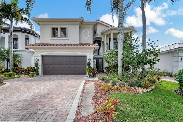 mediterranean / spanish house with a balcony, a garage, and a front lawn