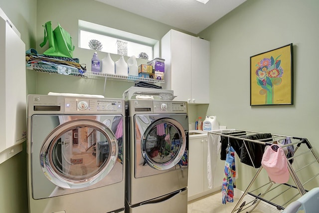 clothes washing area featuring separate washer and dryer and cabinets