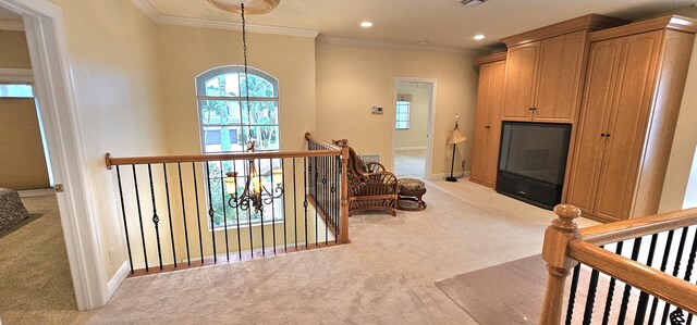 hall with ornamental molding, a chandelier, and light colored carpet