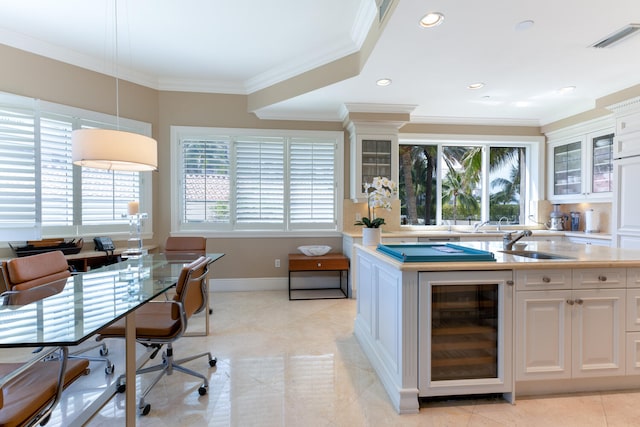 kitchen with light tile flooring, white cabinetry, hanging light fixtures, ornamental molding, and a wealth of natural light