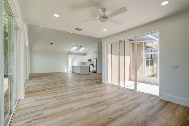 unfurnished living room with sink, light hardwood / wood-style flooring, and ceiling fan