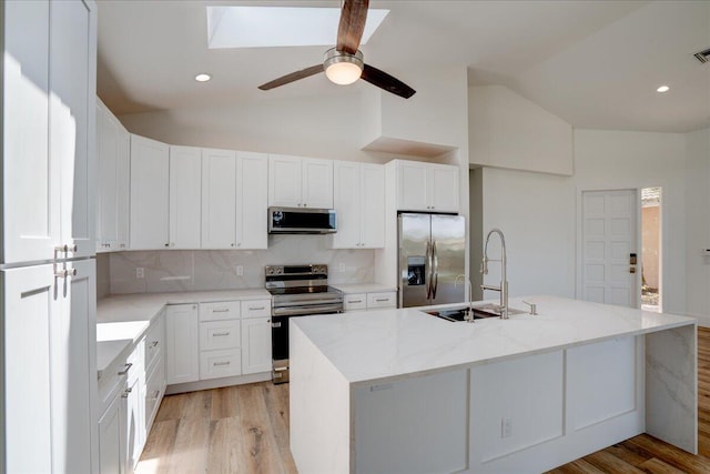 kitchen with white cabinets, light hardwood / wood-style floors, appliances with stainless steel finishes, and backsplash