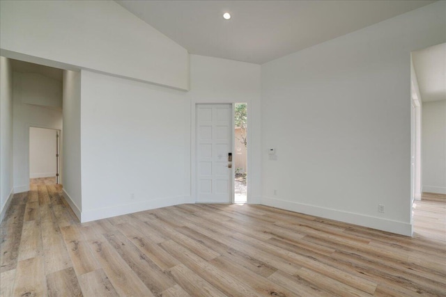 empty room featuring light wood-type flooring and a high ceiling