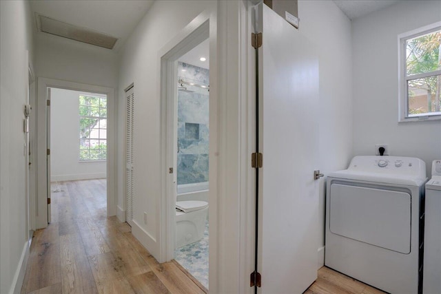 washroom featuring light hardwood / wood-style floors, a healthy amount of sunlight, and washer and clothes dryer