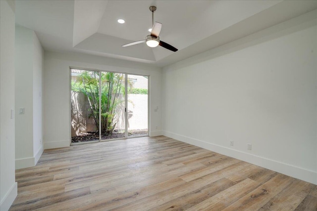 unfurnished room featuring light hardwood / wood-style flooring, ceiling fan, and a tray ceiling