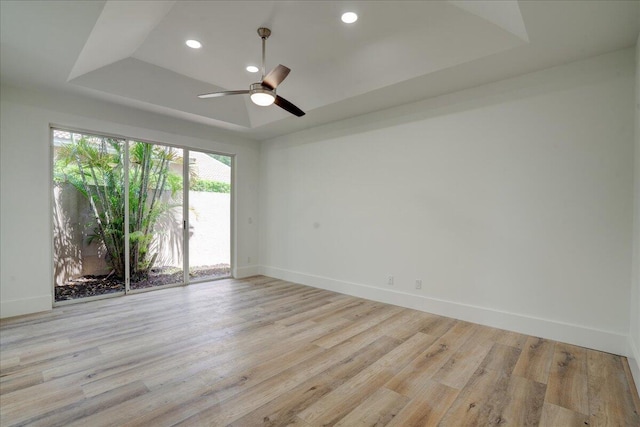 spare room with ceiling fan, a raised ceiling, and light hardwood / wood-style flooring