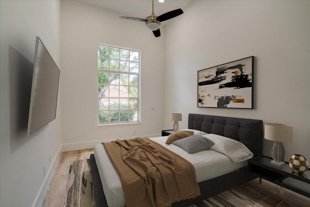 bedroom featuring hardwood / wood-style floors, ceiling fan, and multiple windows