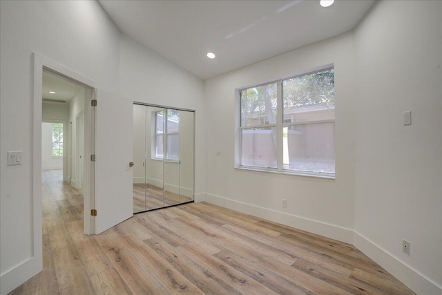 unfurnished bedroom with lofted ceiling, light hardwood / wood-style flooring, and multiple windows