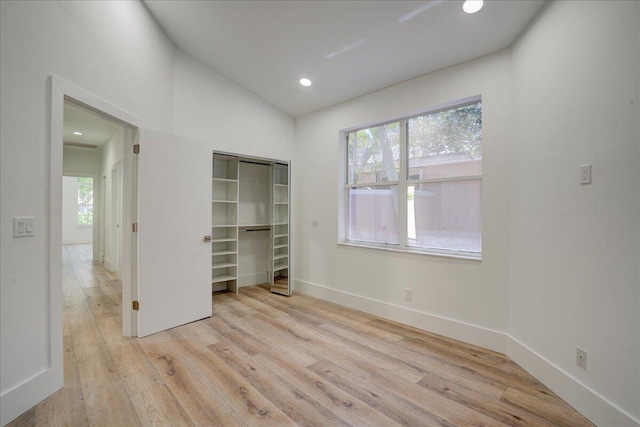 unfurnished bedroom with lofted ceiling, light hardwood / wood-style flooring, and multiple windows