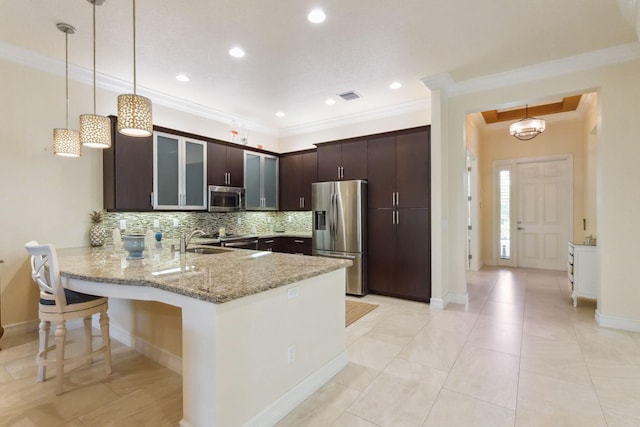 kitchen with dark brown cabinetry, stainless steel appliances, light stone counters, kitchen peninsula, and ornamental molding