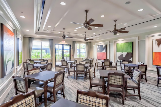 dining space featuring a tray ceiling, ceiling fan, ornamental molding, and light wood-type flooring