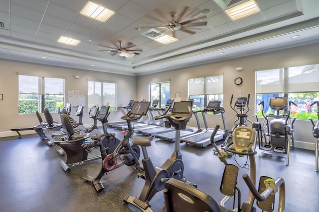 gym featuring a paneled ceiling, ceiling fan, and a raised ceiling