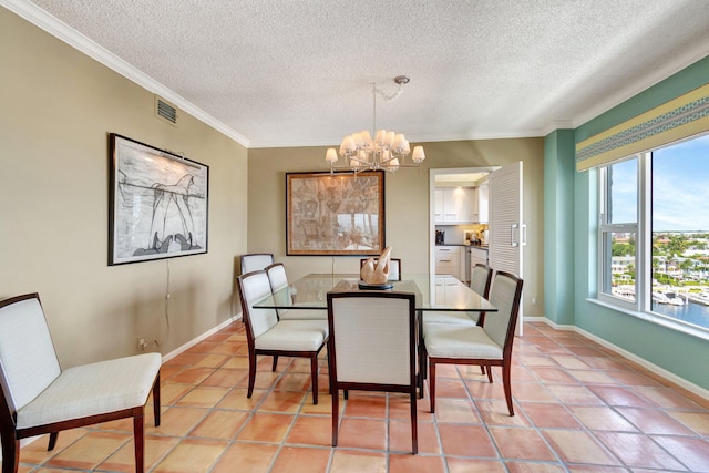 dining area with a textured ceiling, a notable chandelier, crown molding, and tile patterned floors