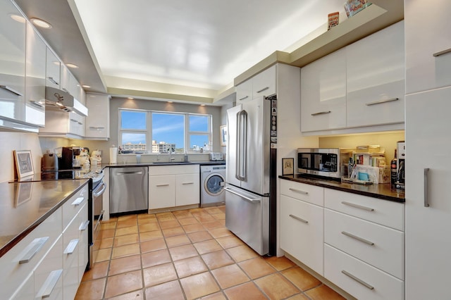 kitchen with white cabinetry, sink, stainless steel appliances, washer / dryer, and light tile patterned floors