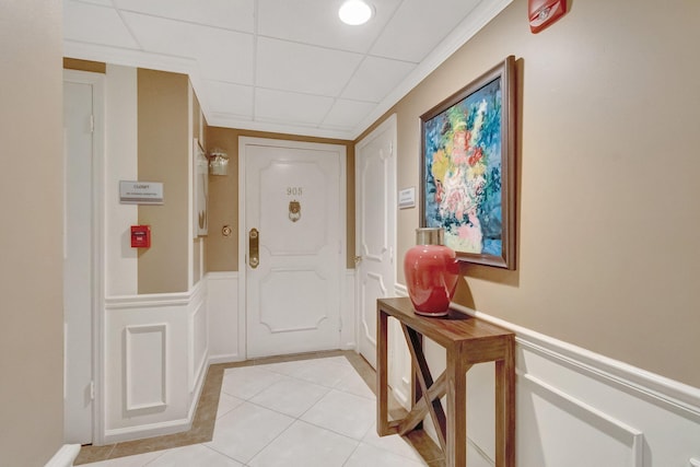 doorway to outside with a drop ceiling and light tile patterned flooring