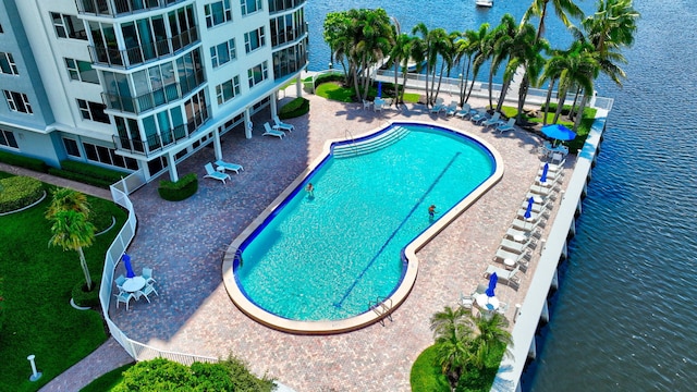 view of pool with a water view and a patio