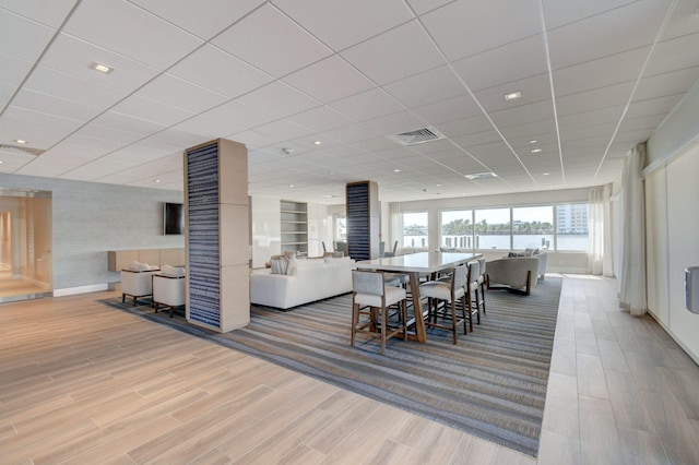 dining room featuring a paneled ceiling and light hardwood / wood-style flooring