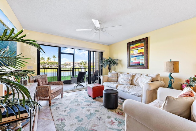 living room featuring a water view, light tile patterned floors, ceiling fan, and a textured ceiling