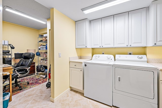 clothes washing area featuring cabinets, washer and dryer, and light tile patterned floors