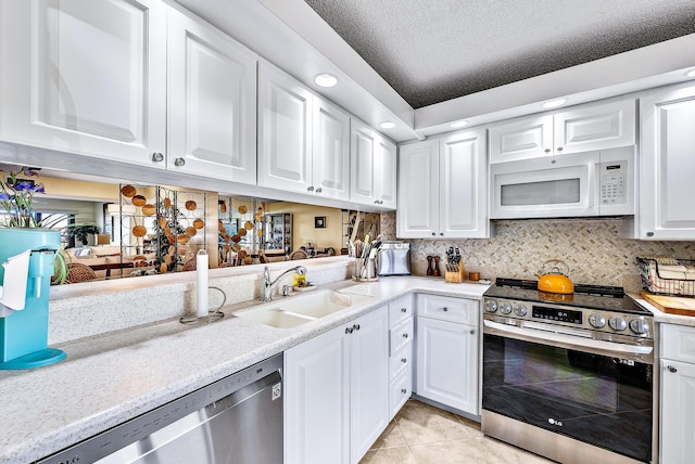 kitchen featuring sink, appliances with stainless steel finishes, white cabinets, light tile patterned flooring, and decorative backsplash