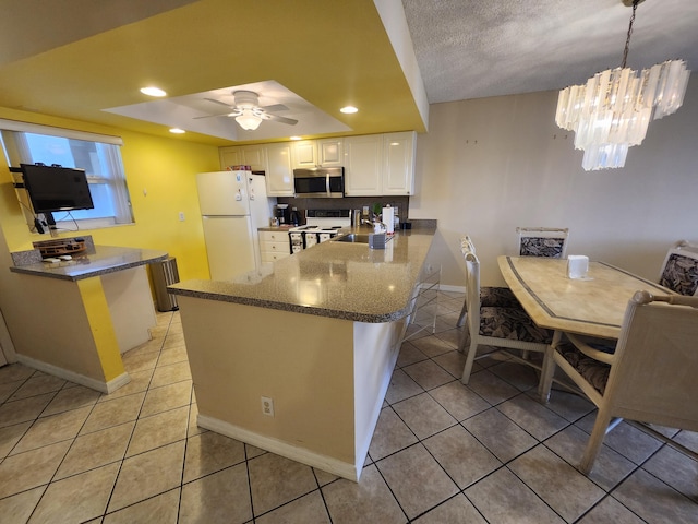 kitchen featuring white cabinetry, kitchen peninsula, decorative light fixtures, white appliances, and ceiling fan with notable chandelier